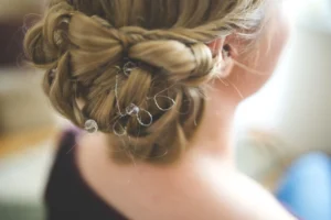 Chignon bas flou sur cheveux mi-longs, rehaussé d'épingles en perle, photographié pendant la préparation de la mariée
